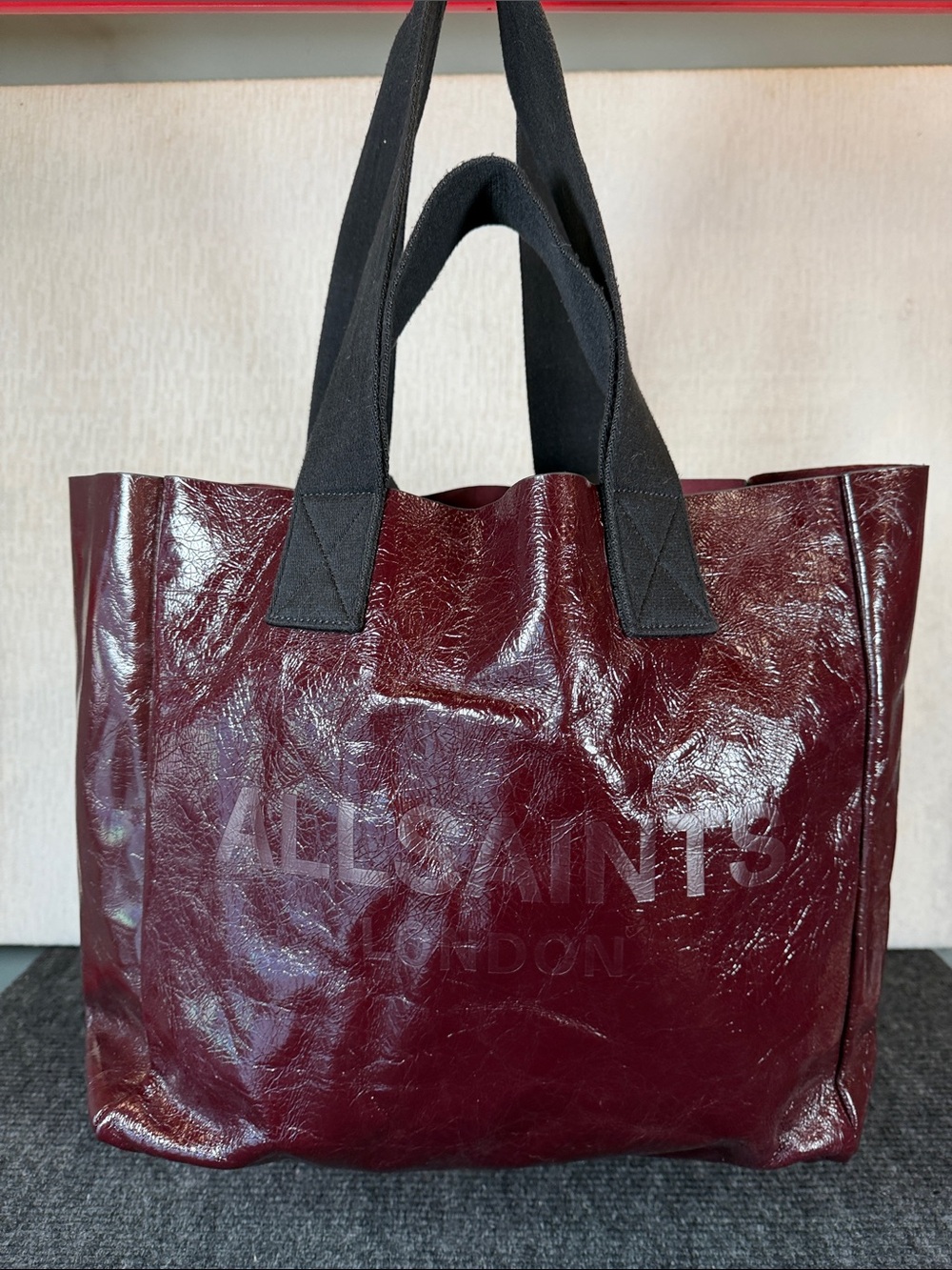 AllSaints Izzy Patent Leather Tote in burnt red.